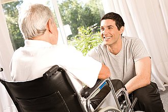 Mann im Rollstuhl mit Pflegeperson